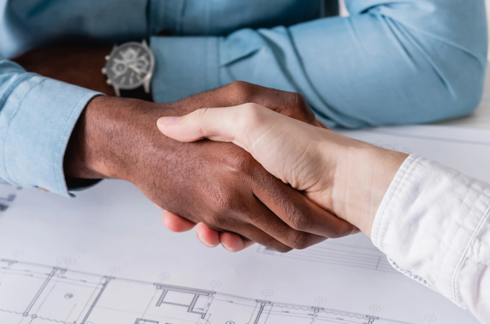 Men shaking hands over a blueprint