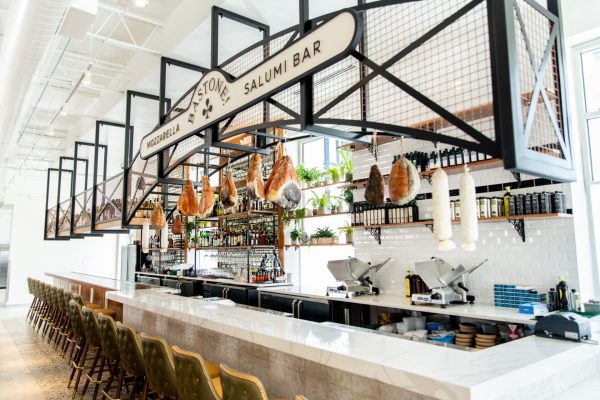 Designed to resemble a brasserie, white tile with a black stripe accent adorns the wall behind the mozzarella bar. The bar
die wall is covered in a textured, dimensional cracked roman look in a muted palette.