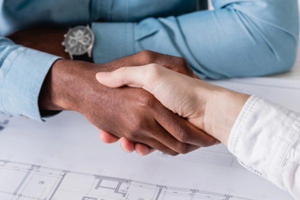 Men shaking hands over a blueprint